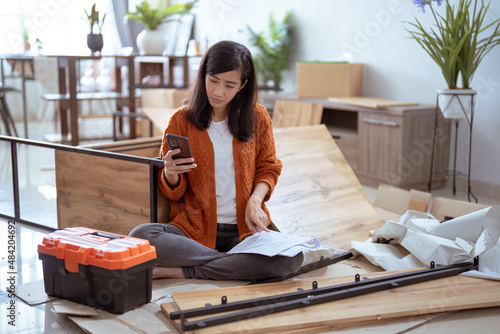 Canvas Print frustrated asian woman while assembling new furniture