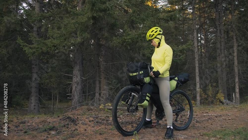 The woman travel on mixed terrain cycle touring with bike bikepacking. The traveler journey with bicycle bags. Magic forest park. photo