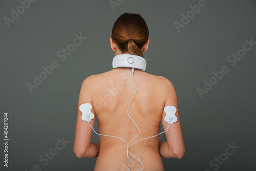 White woman with neck and hand massager. Massager with electrodes on the hands.