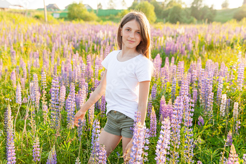 Happy teenage girl smiling outdoor. Beautiful young teen woman resting on summer field with blooming wild flowers green background. Free happy kid teenager girl, childhood concept