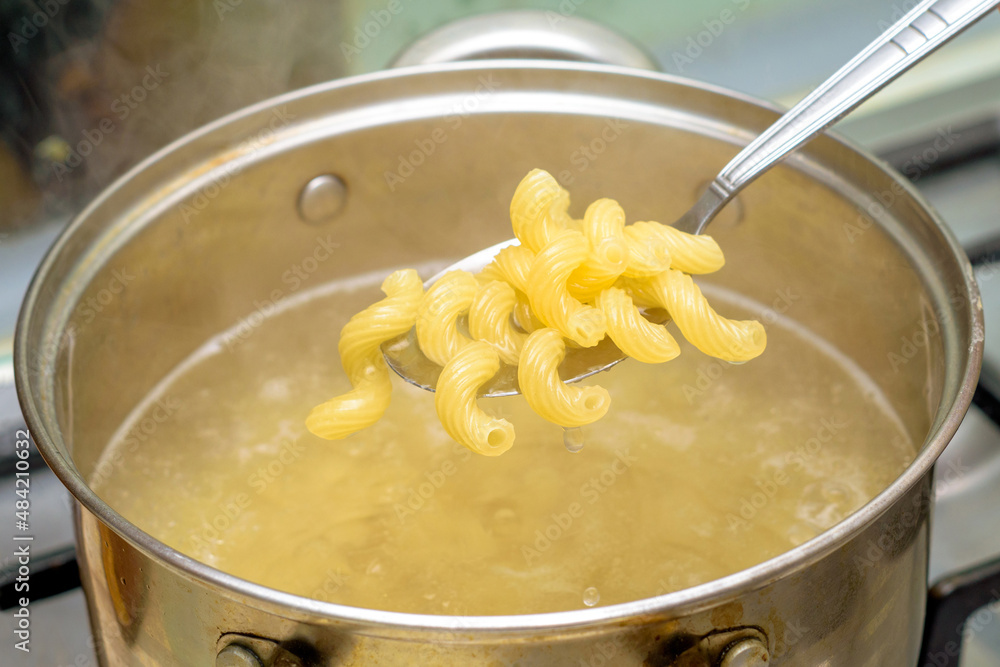 boiled hot pasta in a spoon over a pot of boiling water boiled hot pasta in a spoon over a pot of boiling water