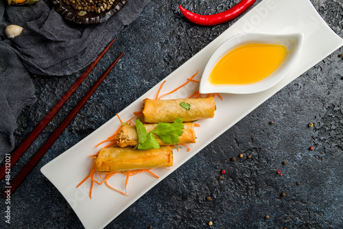 Spring rolls fried with shrimps and sauce on dark stone table, Chinese cuisine top view