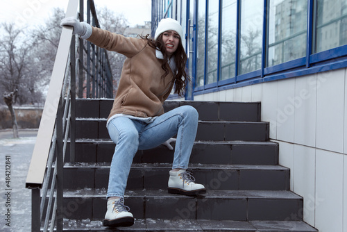 Canvas Print Young woman fallen on slippery stairs covered with ice outdoors