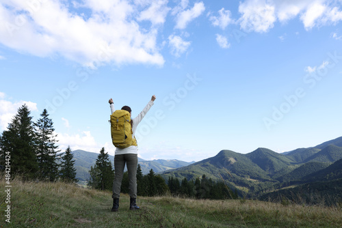 Triumphant tourist on top of mountain, back view. Space for text © New Africa