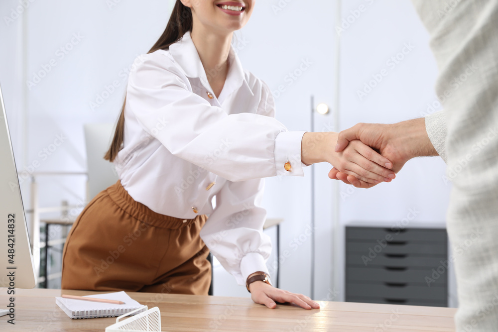 Fototapeta premium Employee shaking hands with intern in office, closeup