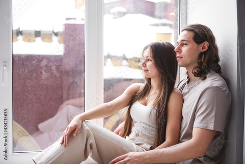 Couple sitting on the windowsill. Couple looking out the window. Couple in love