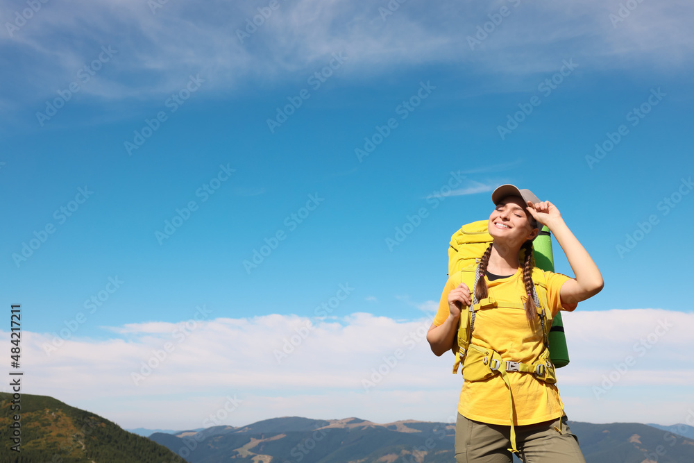 Young woman with backpack in mountains. Space for text