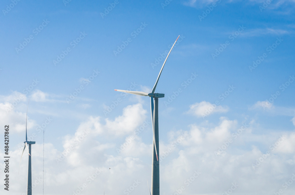 Windmills during bright summer day with blue sky, clean and renewable energy concept. Windmills during bright summer day with blue sky, clean and renewable energy concept.