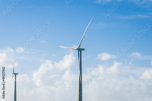 Windmills during bright summer day with blue sky, clean and renewable energy concept.