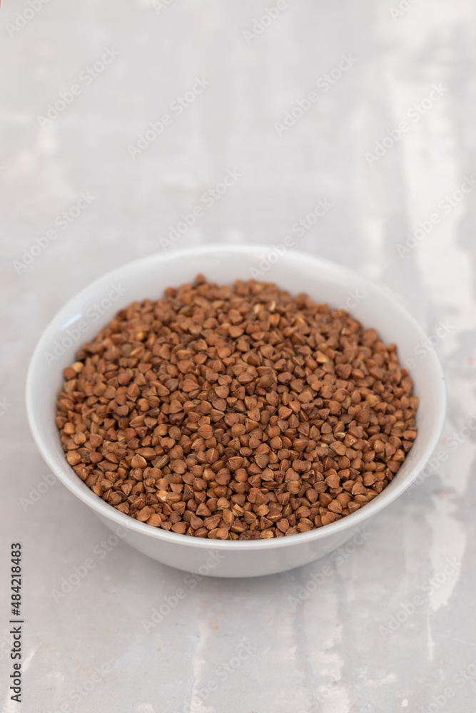 uncooked buckwheat in small white bowl on ceramic uncooked buckwheat in small white bowl on ceramic