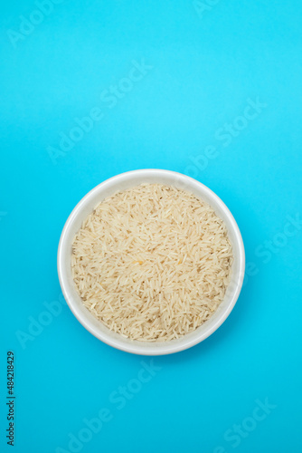 raw rice on white small bowl on blue