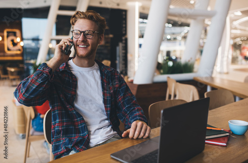 Young caucasian guy talking on smartphone at table