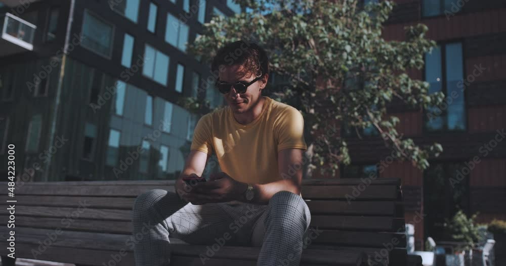 Man sits on bench with phone Man sits on bench with phone