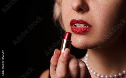 young woman paints her lips with lipstick