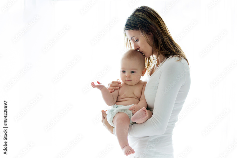Mother, holding her sick baby boy, sad baby, isolated on white Mother, holding her sick baby boy, sad baby, isolated on white