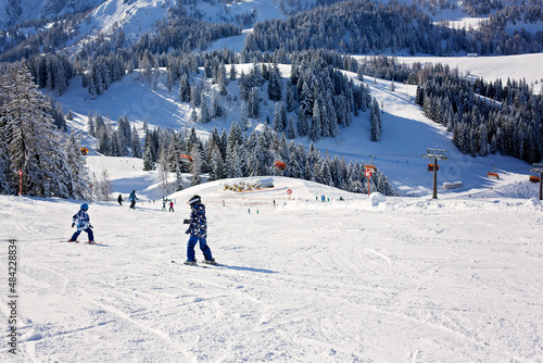 Cute preschool children, skiing in Austrian winter resort on a clear day, wintertime