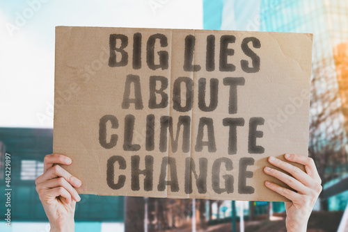 Foto The phrase  Big lies about climate change  on a banner in men's hand with blurred sea on the background