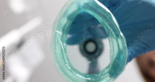 Doctor in medical gloves putting oxygen mask on patient closeup