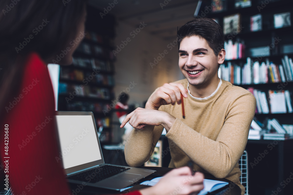 Cheerful man sitting with female student and talking about joint project Cheerful man sitting with female student and talking about joint project