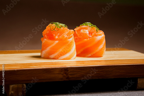Salmon sushi freshly prepared. Japanese food, sushi roll of salmon in a wooden background. Fish and crustaceans slices. Front view with Copy Space.