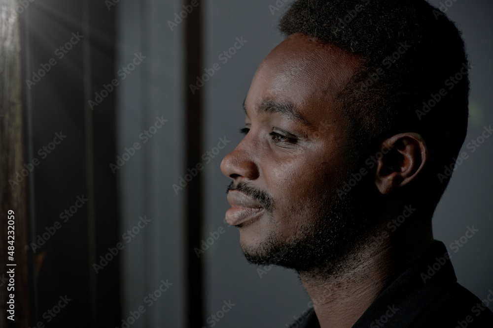 Depressed African man thinking about disappointed love and looking outside.Concept of Broken Heart and Valentine's Day Depressed African man thinking about disappointed love and looking outside.Concept of Broken Heart and Valentine's Day