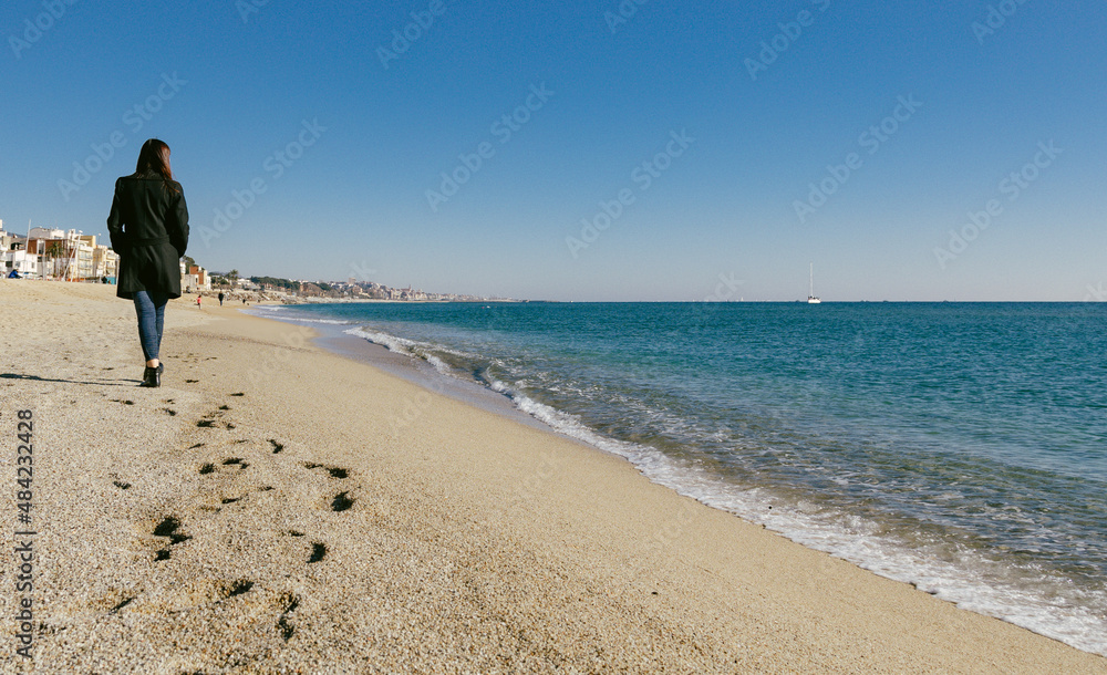 Woman walking on the beach on a sunny winter day