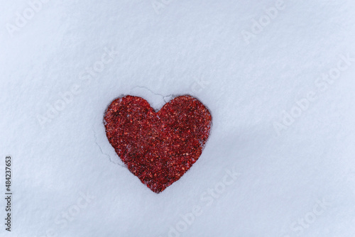 A red meat heart lies on the snow.