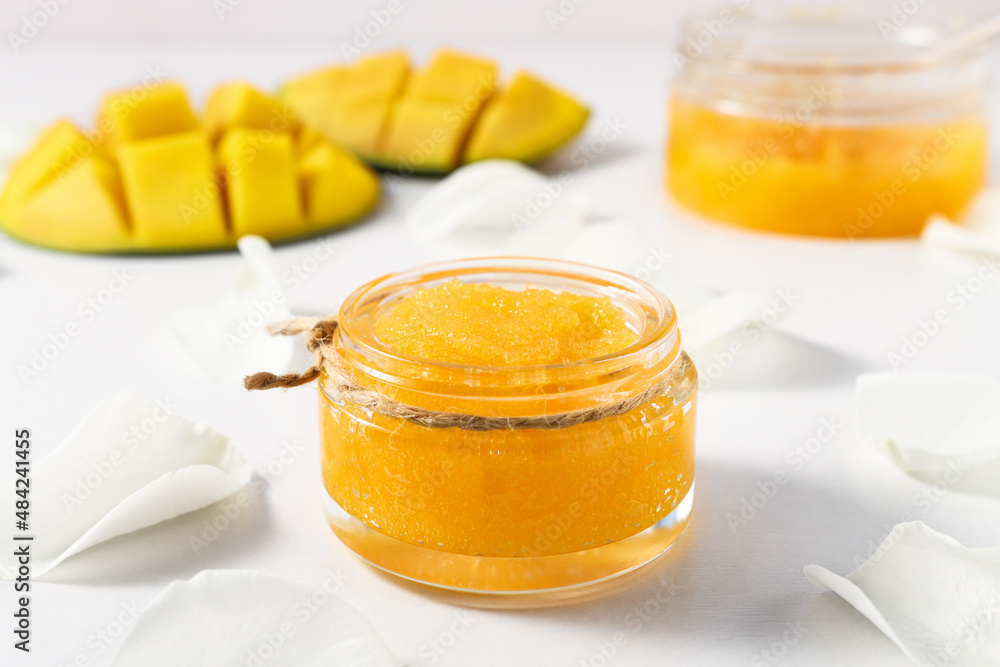 Sugar scrub for spa treatments with mango fruit on a white table close-up. Cosmetics for skin cleansing and body care. Sugar scrub for spa treatments with mango fruit on a white table close-up. Cosmetics for skin cleansing and body care.
