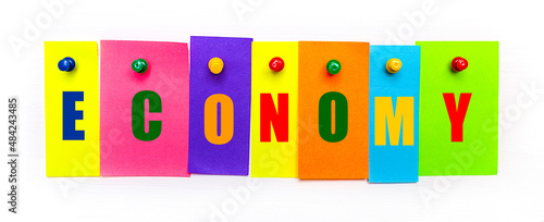 On a white background  buttons are used to fix bright multi-colored strips of paper with the text ECONOMY