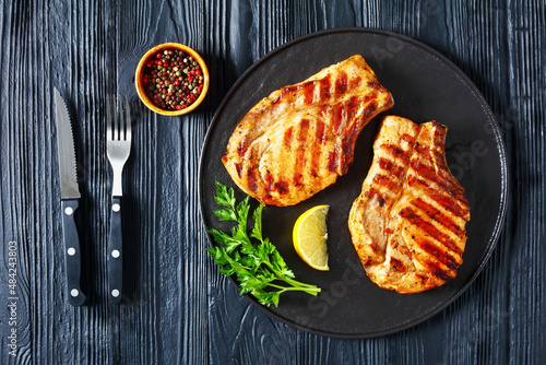 Photos grilled bone-in pork chops on a black plate