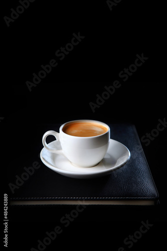 A cup of coffee is on a notepad for notes.Top view.Business breakfast.Food and drinks.Coffee break. Space for copying.Flat lay.Vertical photo.