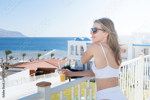 Fit sexy attractive woman looking at the seaside drinking cocktail