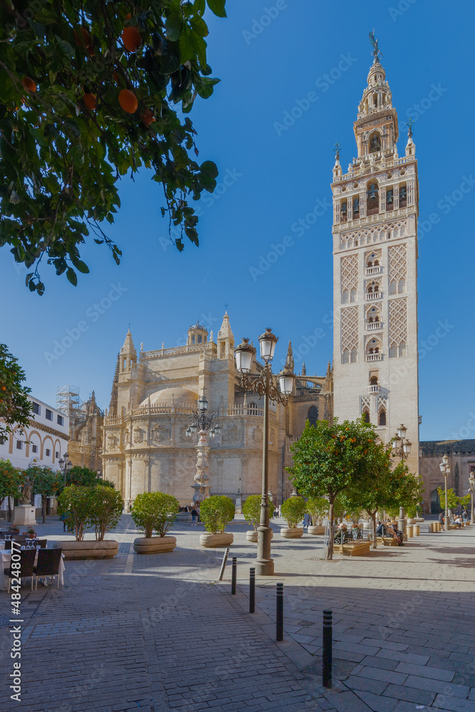 A view on the historic La Giralda tower in the heart of Seville surrounded with the typical orange trees. This iconic landmark can be seen throughout the city. 