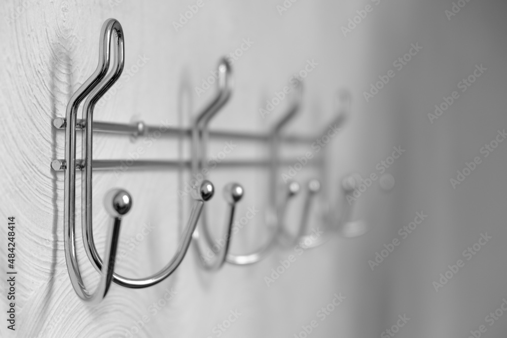 Fototapeta premium Extremely close-up metal coat hooks on white wall, selective focus