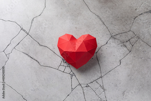 Red paper heart isolated on grey cracked concrete background