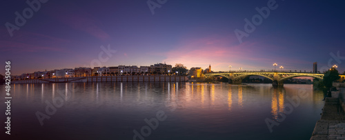 Sunset over the river Guadalquivir in downtown Seville with amazing colors in the sky and a view on the riverside of  the Triana neighbourhood. © KimWillems