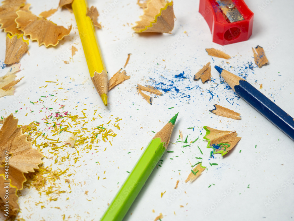 School supplies. Pencil sharpening. Multicolored pencils on a white background. Wood shavings. The process of preparing for work. Creative mess School supplies. Pencil sharpening. Multicolored pencils on a white background. Wood shavings. The process of preparing for work. Creative mess