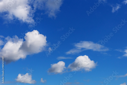blue sky with white cumulus clouds of various sizes as a natural background