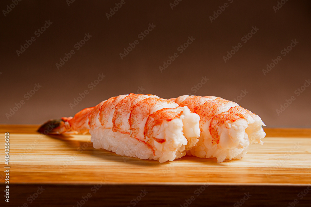Sushi freshly prepared. Japanese food, sushi roll of shrimp in a wooden background. Fish and crustaceans slices. Front view with Copy Space. Sushi freshly prepared. Japanese food, sushi roll of shrimp in a wooden background. Fish and crustaceans slices. Front view with Copy Space.