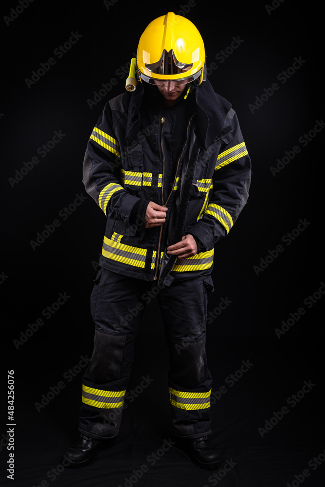 Fototapeta premium Firefighter in full firefighting gear on a black background
