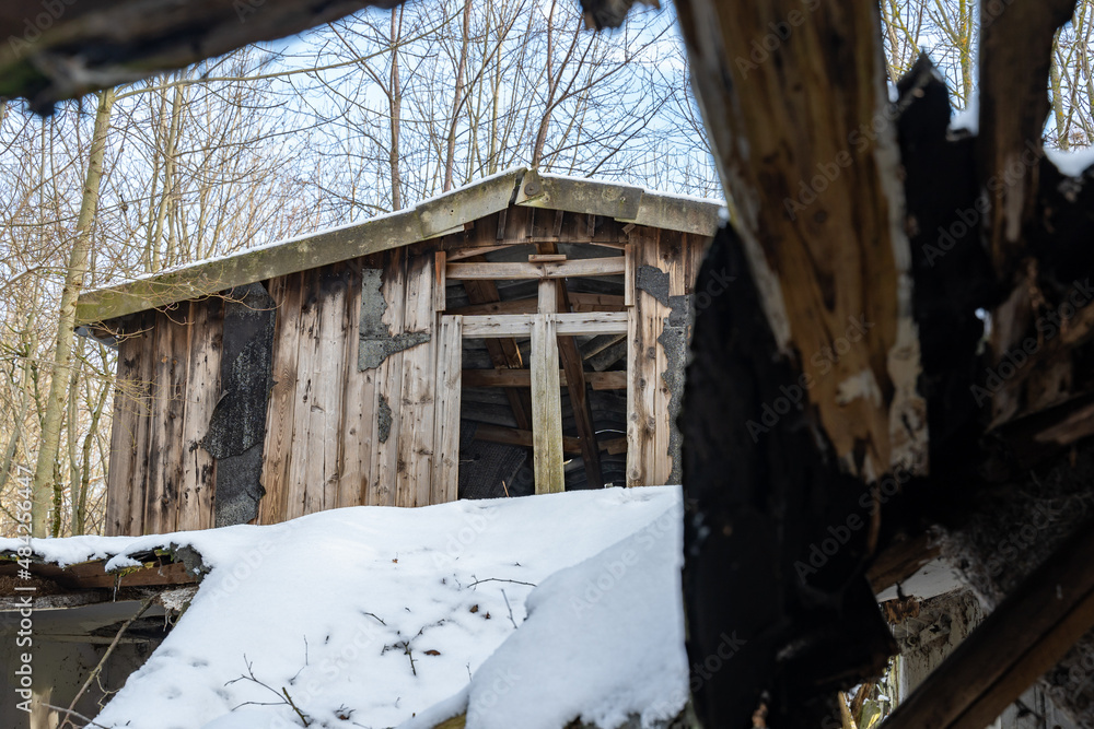 Old wooden cabin in the woodlands is an abandoned building in very bad condition. House made of timber in a rural area. The roof is broken and run-down. Snow is lying on the exterior. Old wooden cabin in the woodlands is an abandoned building in very bad condition. House made of timber in a rural area. The roof is broken and run-down. Snow is lying on the exterior.