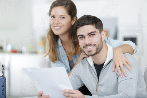 portrait of couple holding paperwork in the home