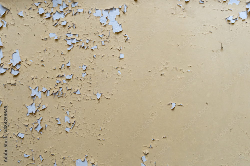 Paint on a beige wall peeling off. Abstract background of a vintage wall inside in an abandoned building. Interior design texture of a ruin. Backdrop of a weathered material surface. Paint on a beige wall peeling off. Abstract background of a vintage wall inside in an abandoned building. Interior design texture of a ruin. Backdrop of a weathered material surface.