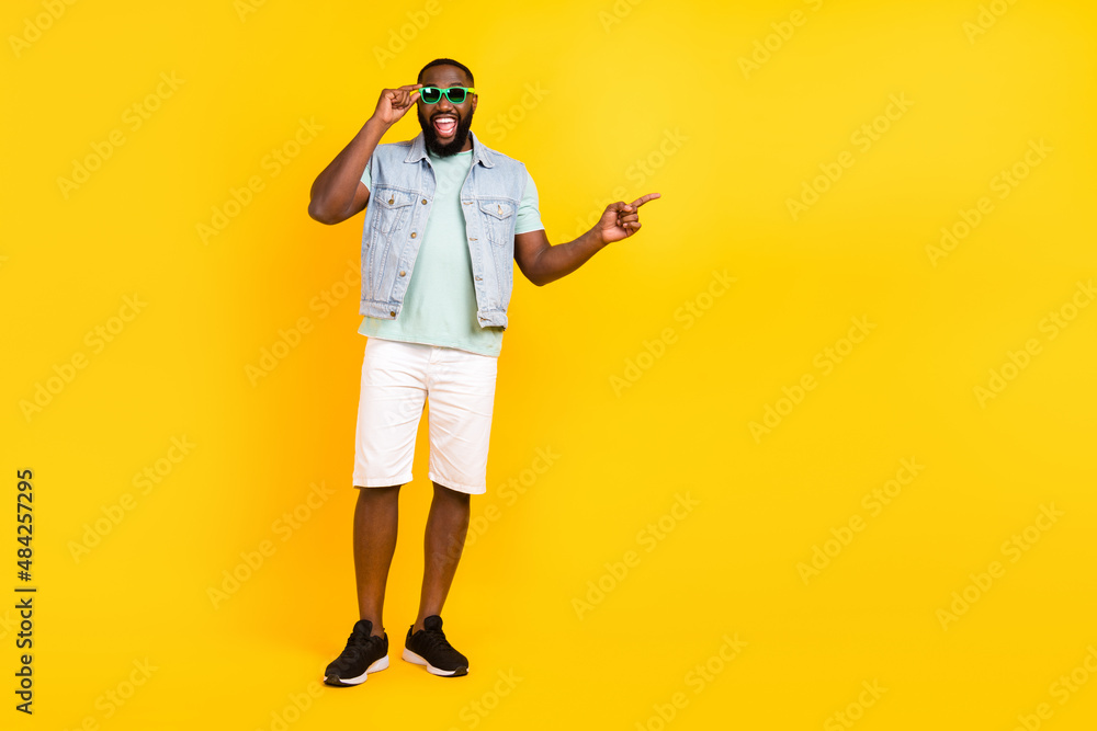 Fototapeta premium Full length body size view of handsome trendy cheery guy showing copy space isolated over bright yellow color background
