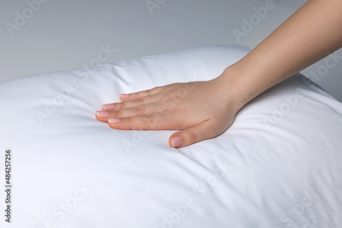 Woman touching soft white pillow on bed  closeup