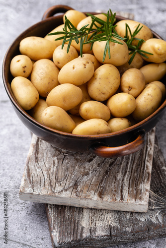 Raw small potatoes in a cast iron skillet on a beton background.