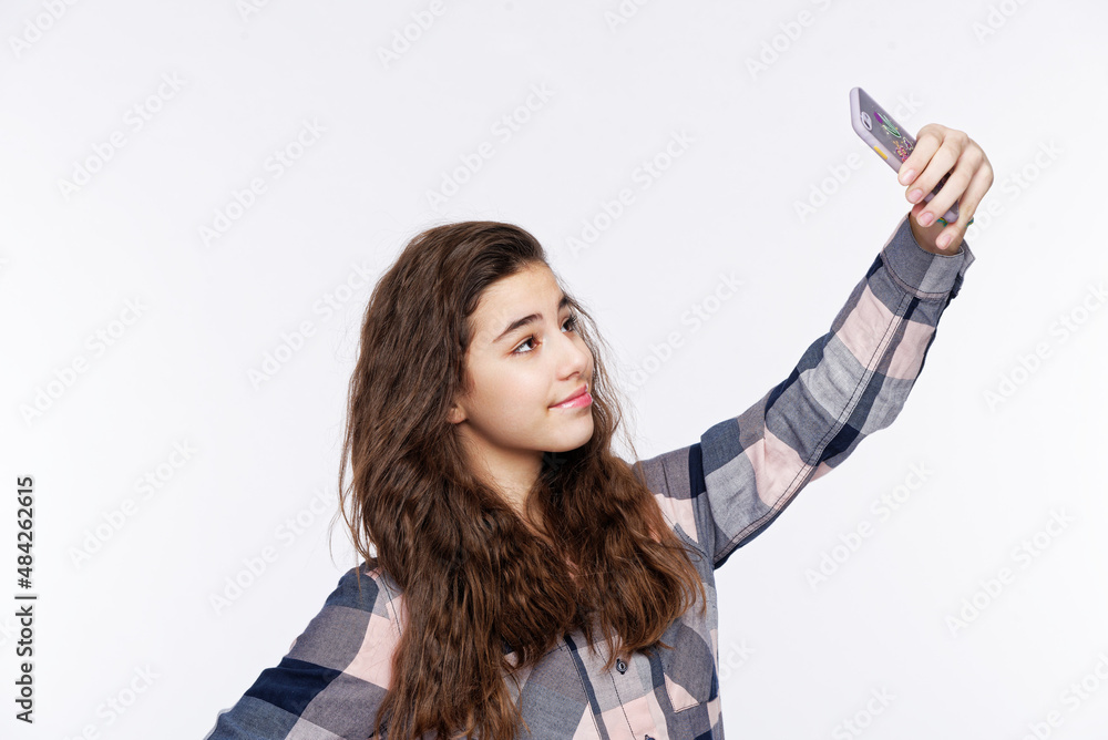Naklejka premium A curly-haired teenage girl taking a selfie, studio white background