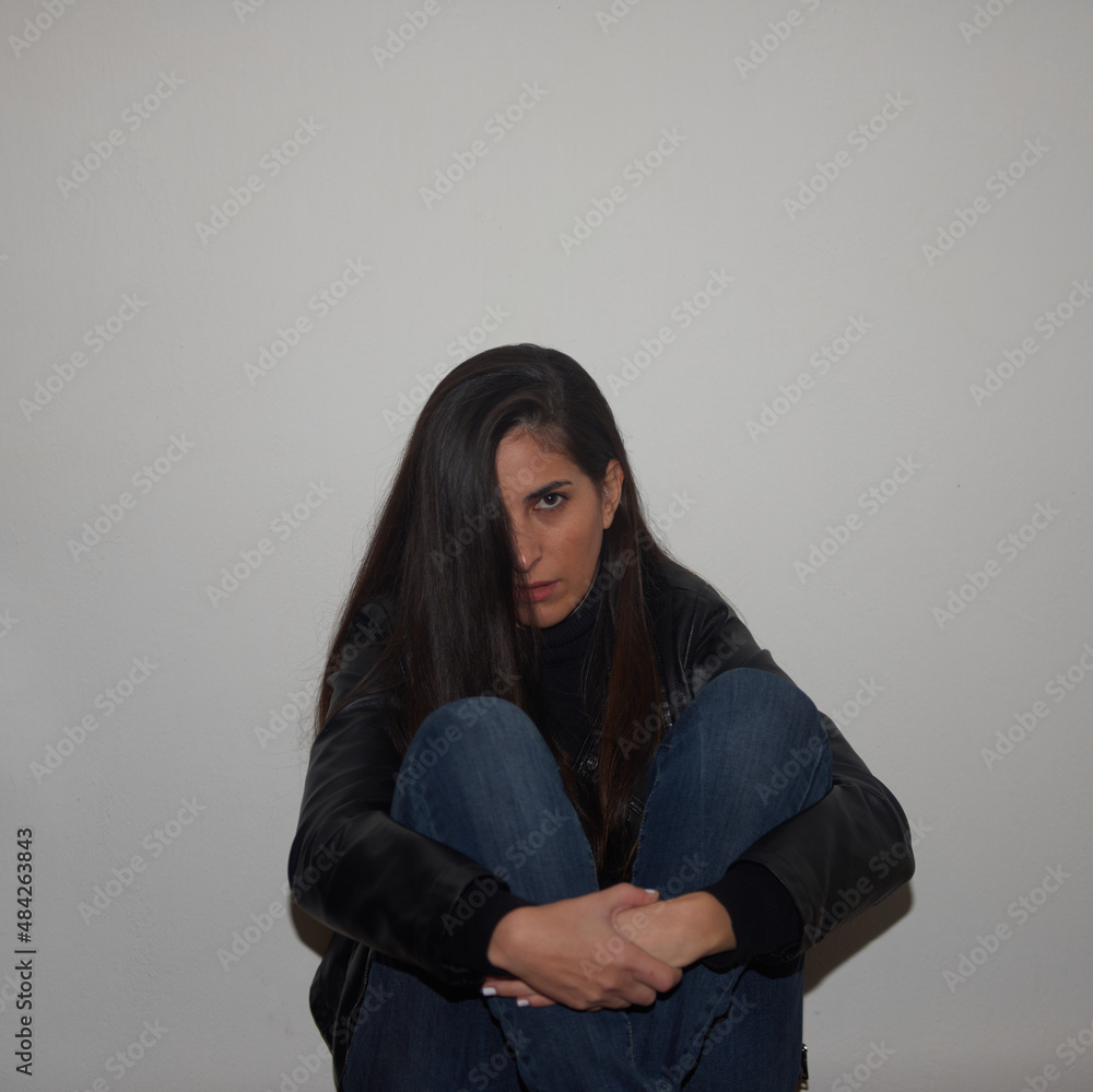 A woman seated and hugging her knees A woman seated and hugging her knees