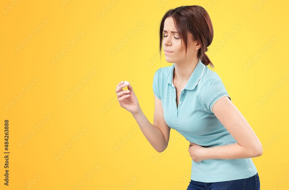 Young woman with arms on stomach and bending over with menstrual pain expression Young woman with arms on stomach and bending over with menstrual pain expression