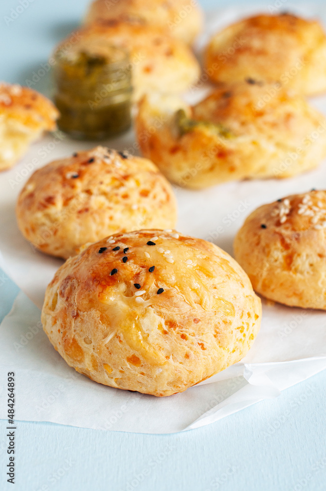 Homemade small cheese dinner rolls with sesame seeds on a baking paper.